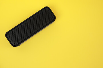 One portable bluetooth speaker on yellow background, top view with space for text. Audio equipment
