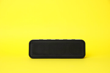 One portable bluetooth speaker on yellow background, space for text. Audio equipment