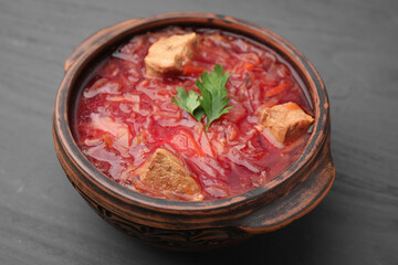 Tasty borscht in bowl on grey wooden table, closeup