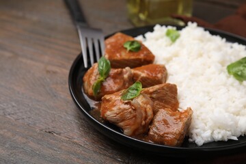 Delicious goulash served with rice on wooden table, closeup