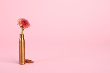 Bullet cartridge case and beautiful chrysanthemum flower on pink background, space for text - obrazy, fototapety, plakaty