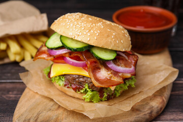 Tasty burger with bacon, vegetables and patty on wooden table, closeup