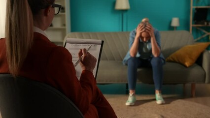 Back view of a female psychologist against a blurred background of a patient sitting on a couch in front of her. Disappointed woman depressed, complaining to the specialist about her problems.
