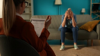 Back view of a female psychologist against a blurred background of a patient sitting on a couch in...