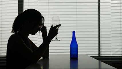 A young woman with glasses is sitting at a table in a cafe thinking about something, a bottle and...