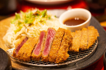 Close up of a plate of fried beef steak served with fresh vegetables salad and sauce, Osaka, Japan