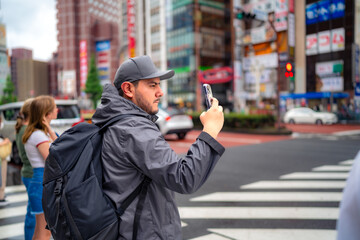 Side view of concentrated young Hispanic male tourist in warm clothes and cap with backpack taking...