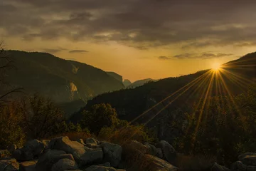 Fotobehang Half Dome Sunburst on mountain top and half dome in the far background with rock formations of the Yosemite Valley 