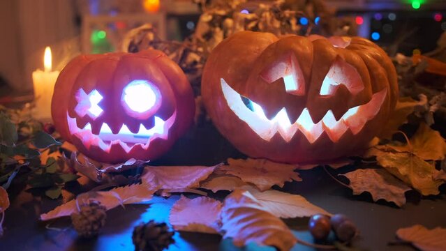 Two carved pumpkins of different sizes creepy smiling glowing mouth burning red devilish light mysterious mystical background for Halloween party celebration.