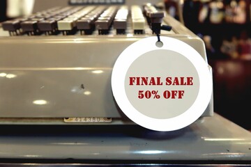An old vintage cashier machine with a tag and a written message text FINAL SALE 50% OFF, concept of...