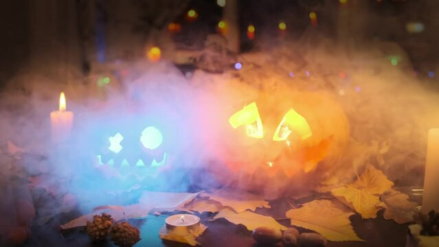 Halloween background with Jack O Lanterns sparking light inside, smoke on a dark background. Festival holiday during Halloween party decoration flashing pumpkins. Zooming receding shot.