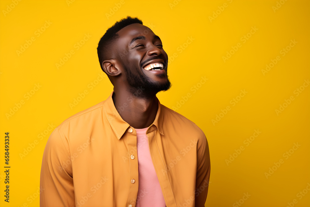 Wall mural colourful portrait of a handsome happy black man laughing and smiling wearing yellow shirt on bright