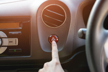 Finger hitting car emergency red light button in the car.
