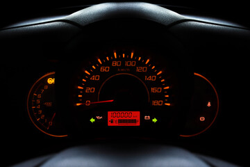 Car dashboard with odometer of car used showing mileage of 100000 km in night