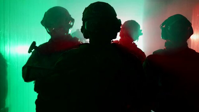 Five fully equipped middle-aged soldiers in camouflage uniforms, they are standing in a ready-to-fire room, aiming rifles. A military operation in action.