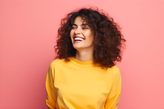 Colourful portrait of a young happy beauty woman laughing and smiling wearing yellow jumper on bright pink background