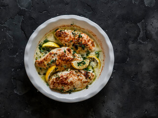 Lemon, thyme, white wine baked chicken breast on a dark background, top view