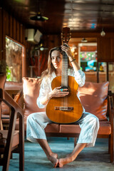 woman okaying posing with guitar in restaurant cafe