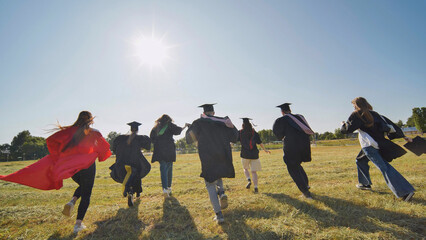 Happy graduates run in and take off their robes. The concept of graduation.