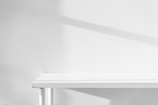 Empty white desk with morning light and shadows of windows with copy space, summer concert. Blurred backdrop abstract background for display product.