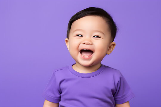 Portrait of a cute Asian American baby boy wearing purple tee shirt laughing on purple background