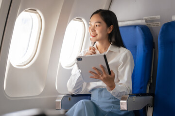 Using tablet pc, Thoughtful asian people female person onboard, airplane window, perfectly capture the anticipation and excitement of holiday travel. chinese, japanese people.