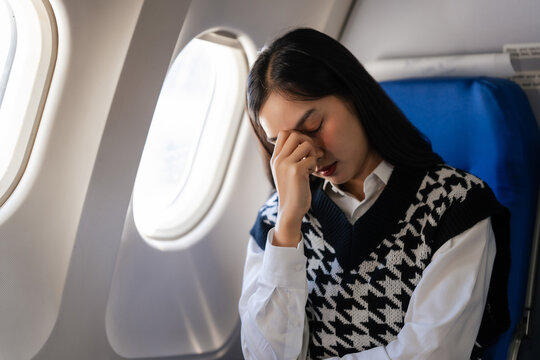 Female asian chinese japanese people passenger experiencing airsickness, clenching sick bag and looking uneasy mid-air.