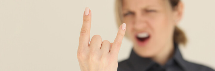 Blurry screaming woman shows horns gesture with fingers