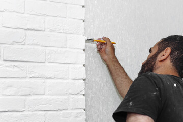 male hand painting white brick wall with paint brush