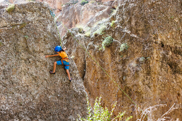Obraz premium climber boy. a child in a helmet climbs a rock. sports on the street.