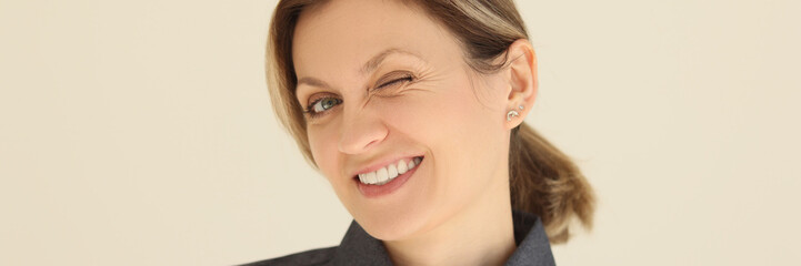 Cheerful woman winks eye looking at camera and smiling