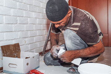 The master applies adhesive tiles to tiling the house. Master builder decorates the walls of the...