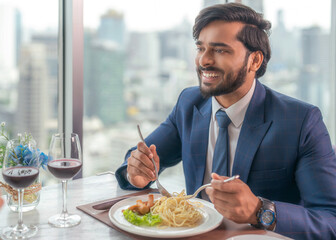 An arab man eating spaghetti in dish on the table in italian restaurant
