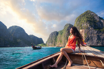 Asian travel woman relax on the traditional long tail boat with maya bay