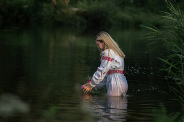 Portrait of a young beautiful blonde girl near a pond.