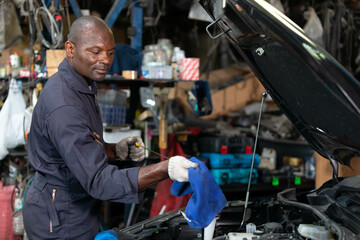 African mechanic worker checking and fixing a car in garage
