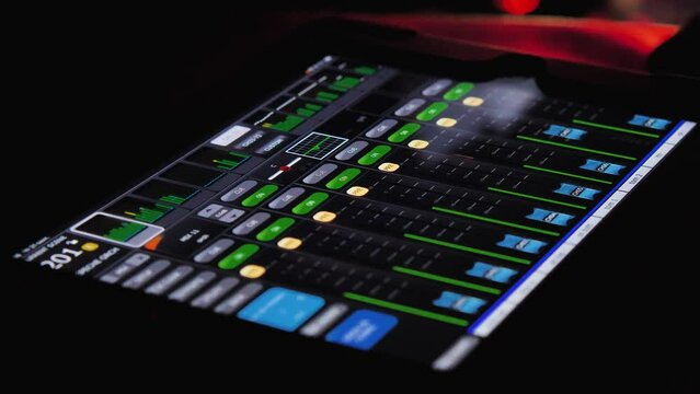 Close-up of a sound control console. Volume levels are running on the tablet screen. The sound engineer takes the tablet in his hands. Remote control of sound parameters on stage