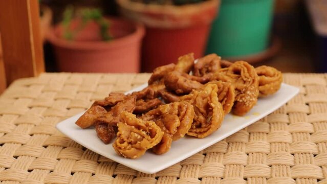 Moroccan chebakias on a white plate in a patio with plants, at home