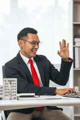 Agent presents contracts for property purchase or lease. Businessman asian indian people showcases miniature model home, signifying secure property insurance. Desk scene in a home sales office.