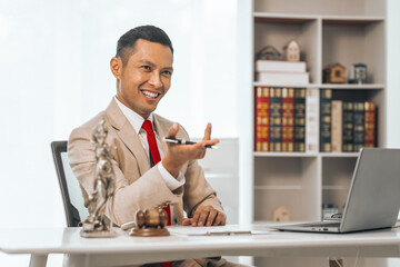Middle-aged Asian indian people male lawyer meticulously reviews legal documents. Courtroom judge hammer and goddess scales. Depicting the essence of legal counseling and comprehensive services.