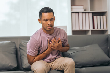 Obraz premium Middle-aged Asian Indian man with Heart disease, sitting on sofas