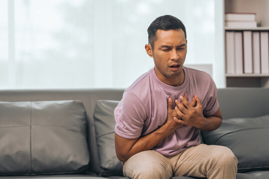 Middle-aged Asian Indian man with Heart disease, sitting on sofas - Powered by Adobe