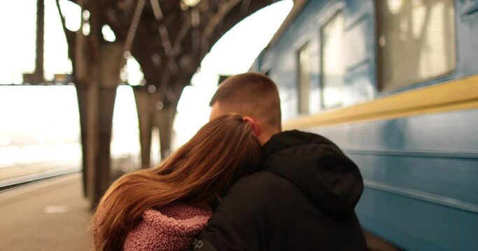A young couple in love hug and say goodbye before the girl gets on the train to leave. Farewell at the station.