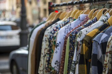 Clothes on the rail on the fashion designer market. Garage sale, reuse the clothes, second hand