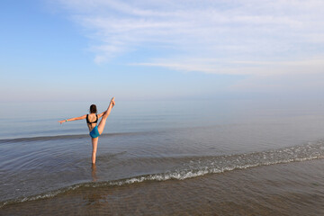 athletic girl with leg up during seaside toilet exercise