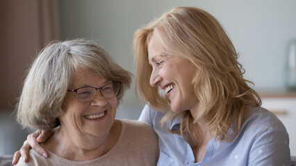 Cheerful elder grey haired 80s mother and grownup mature daughter smiling with love, affection,...