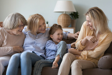 Cheerful excited loving great grandma, grandmother, daughter kid tickling happy young mom, laughing, shouting, playing funny games on couch, enjoying activity, closeness, family leisure