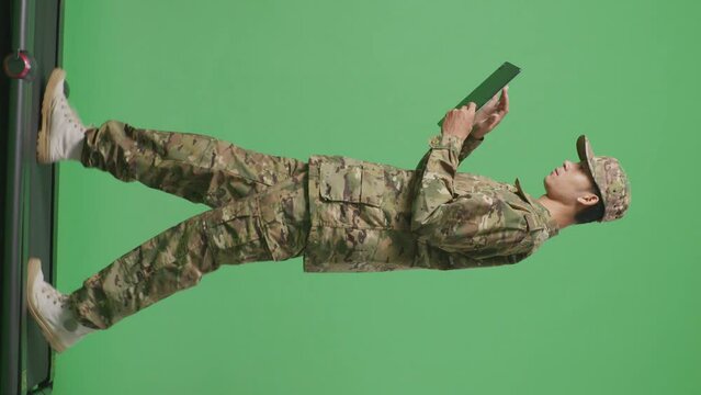 Full Body Of Side View Asian Man Soldier Using A Tablet While Walking In The Green Screen Background Studio
