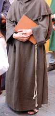 Franciscan friar with the brown dress called habit and the rope around his waist with the sacred book on hand