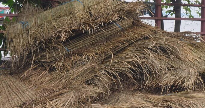 Zoom out of a stack of straw roofs on the ground.